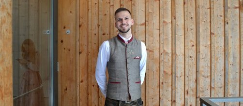 junger Mann mit Bart, weißes Hemd, grau-rotes Gilet